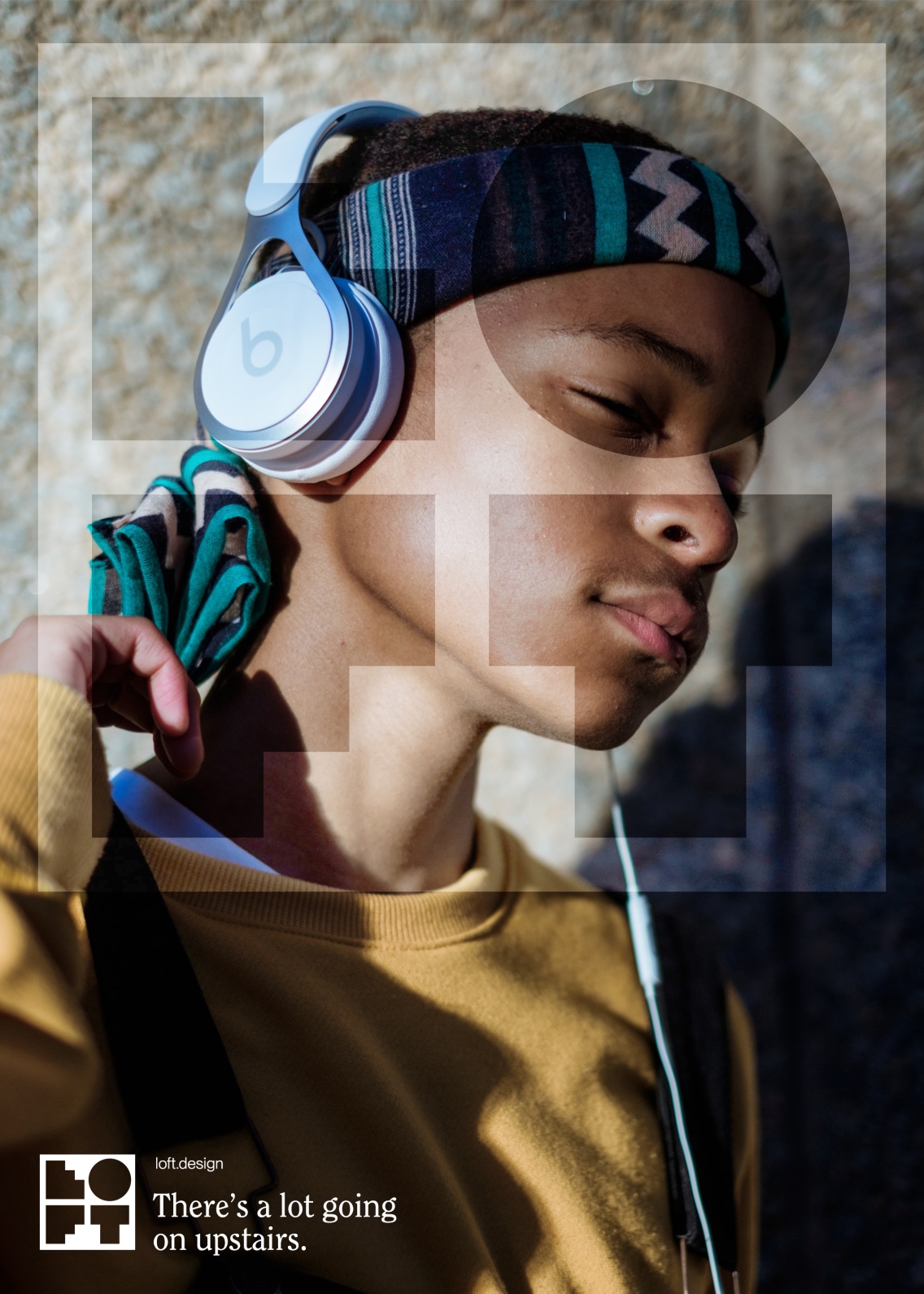 A young man is lost in the music pouring through his Beats headphones. A semi-transparent Loft logo has been placed in the foreground. There's a lot going on upstairs.