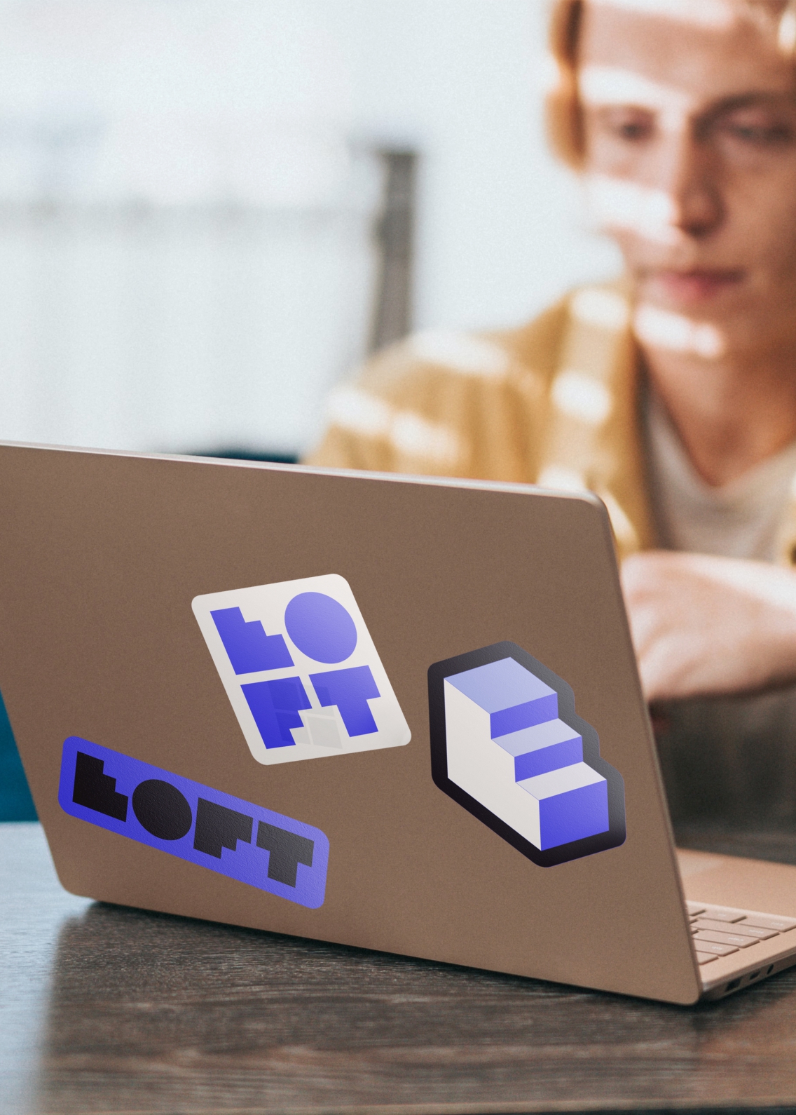 Conceptualised stickers on a mac's cover. In colours of white, electric purple and black, there are variations of the logo and it's prime shape, the climbing stairs.