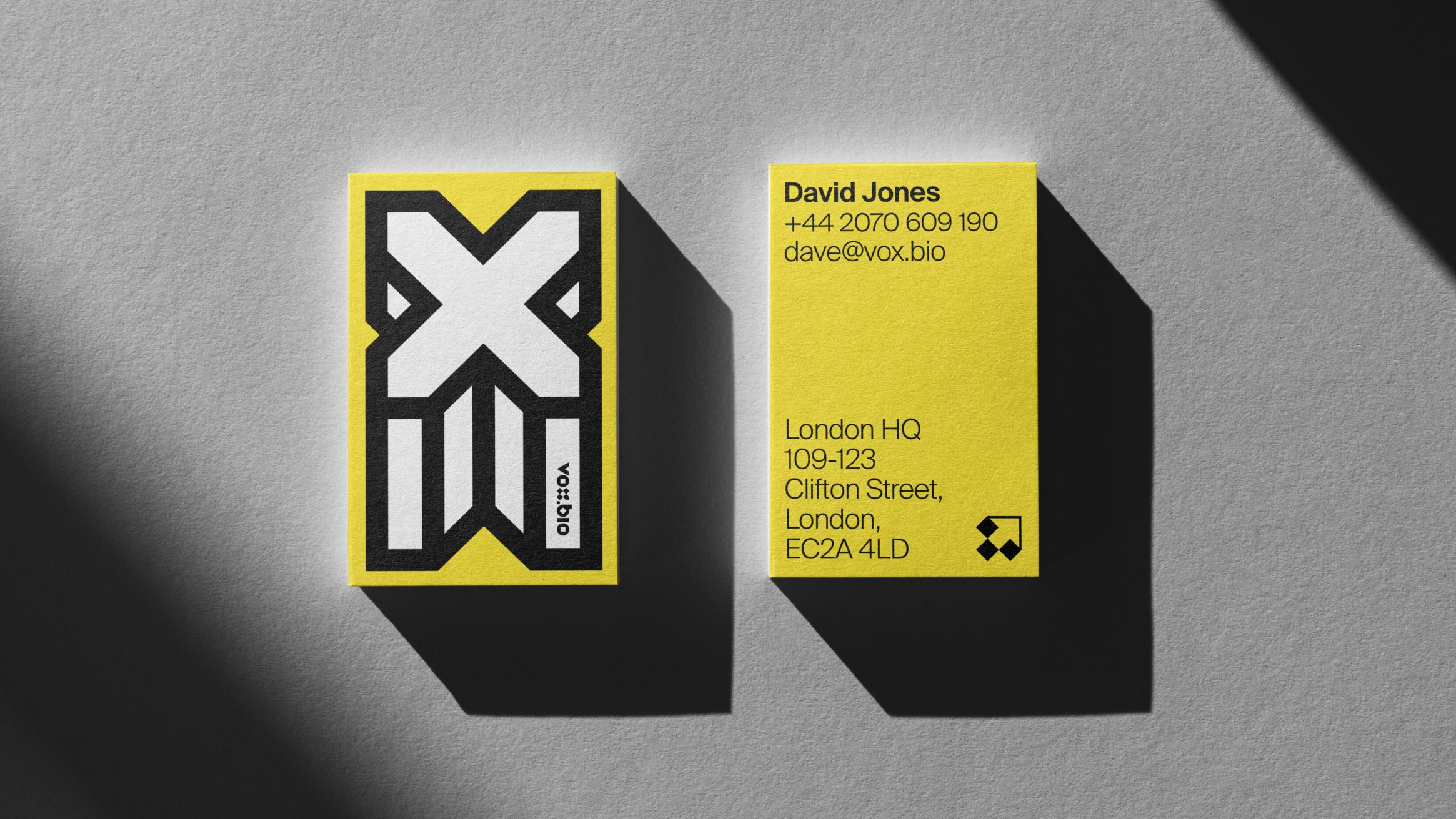 Vox.Bio branded business cards. Bold yellow, simple black text and large white cross icon