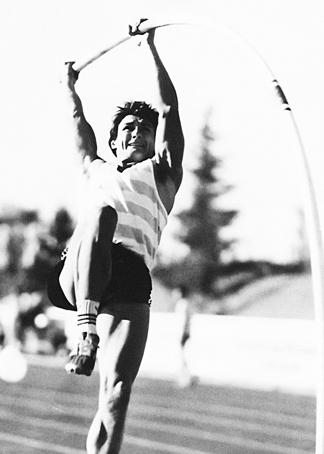 A black and white portrait of a pole vault athlete grasping the pole ready to take flight
