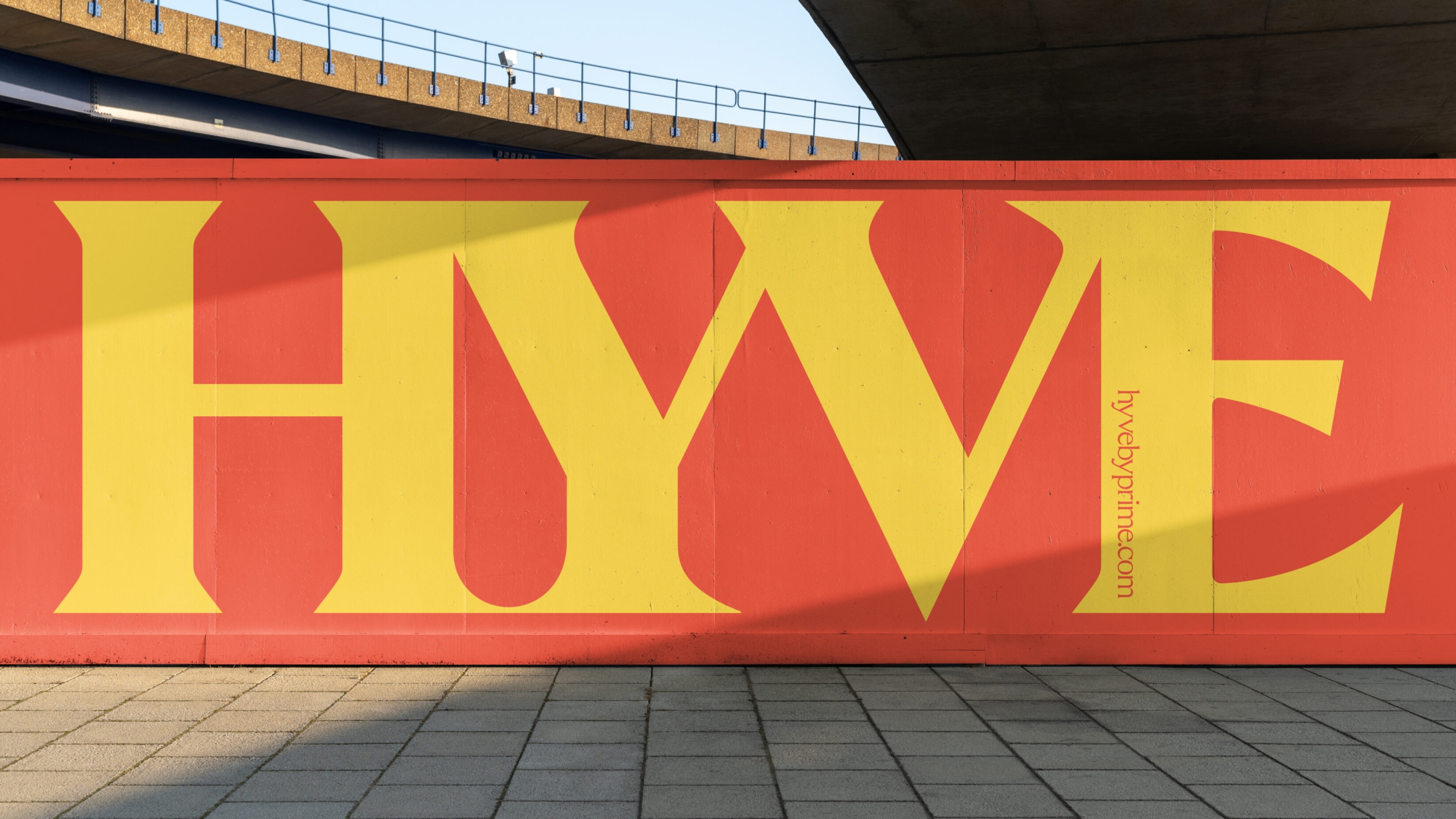On construction site hoarding, the word HYVE full height in yellow, on a red background.