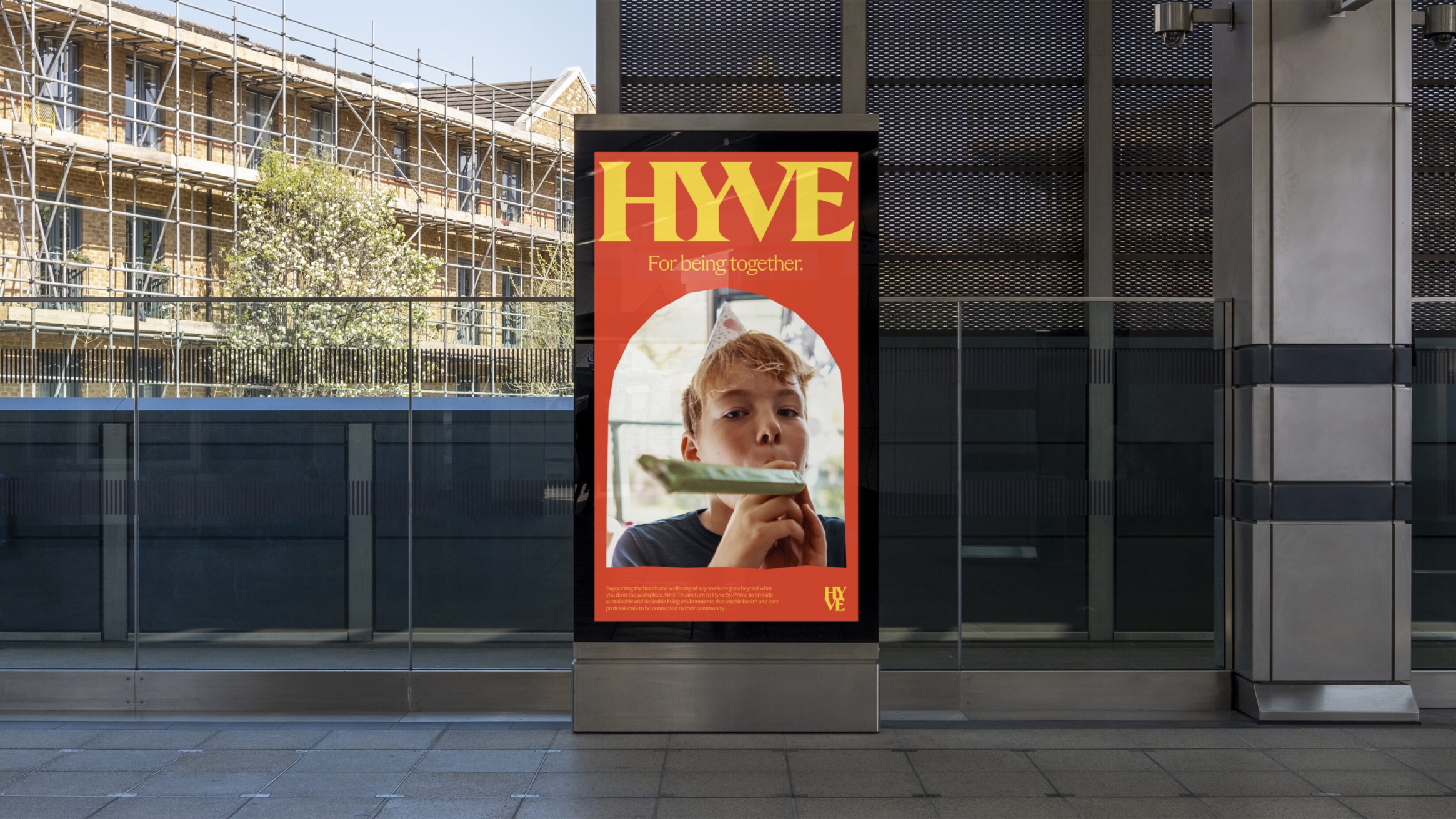 Station digital advert of a young boy at a party, with a party streamer blower. The image is inside an archway graphic, with HYVE large in yellow above it, all on a red background.