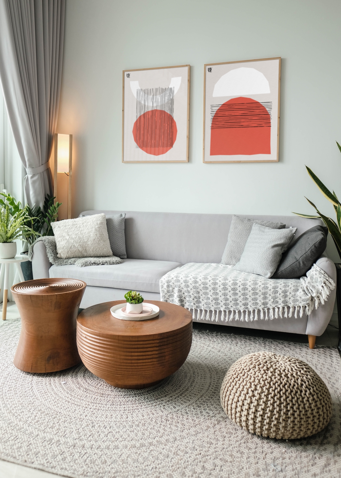 A wartm and cosy home environment, with a grey sofa, a wooden table and two posters on the walls in frames, showing abstract brand shapes.