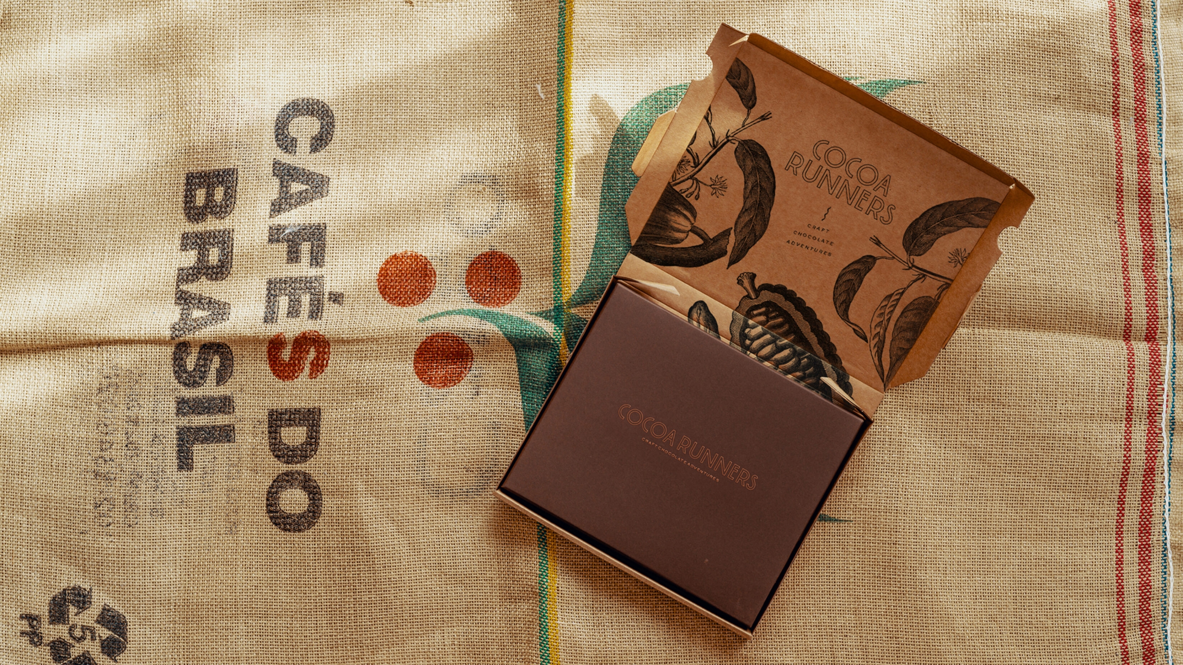 An open packaging box, with the Cocoa Runners logo and cocoa illustartion displayed, showing off the gift box inside.