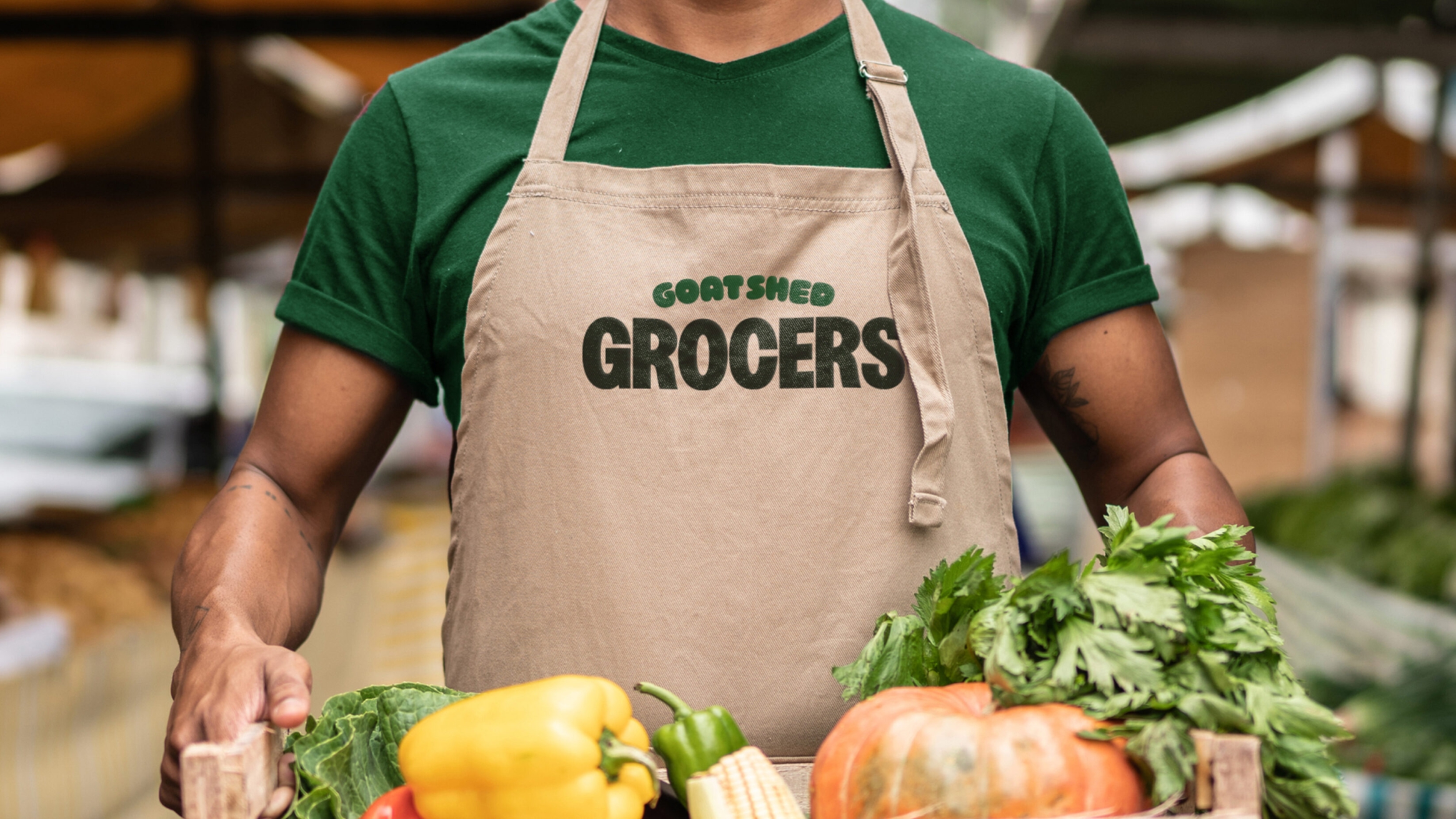 Man holding tray of veg with goat shed apron on